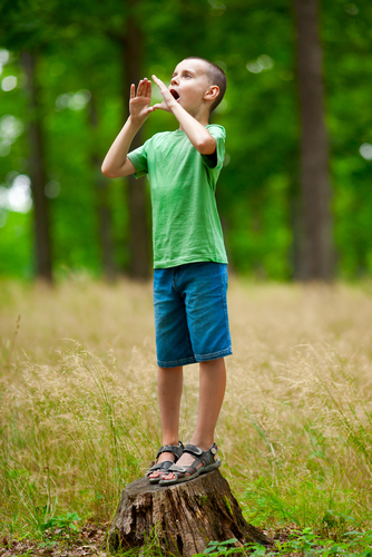 young boy in t shirt shouting in woods